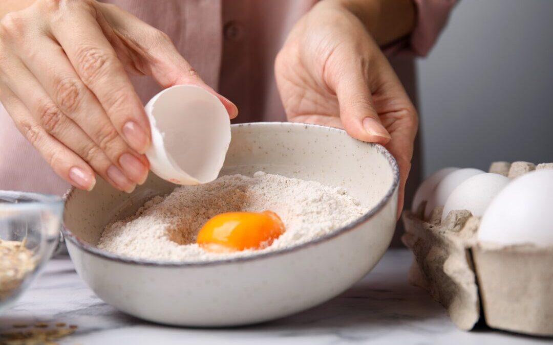 woman adding egg to pancake batter The Great American Pancake Co.
